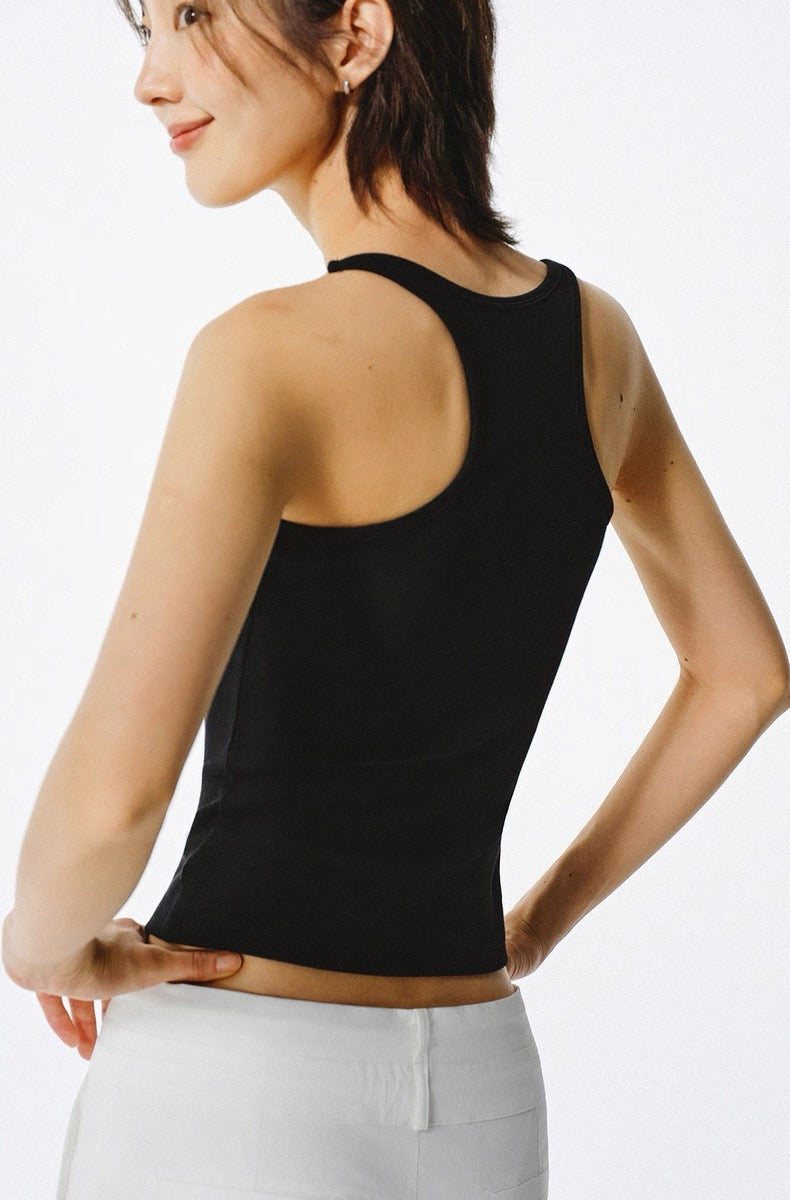Woman wearing a black tank top and white pants on a plain background
