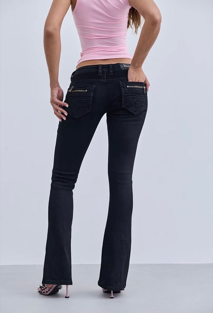 Person wearing black flared jeans and a pink top on a white background