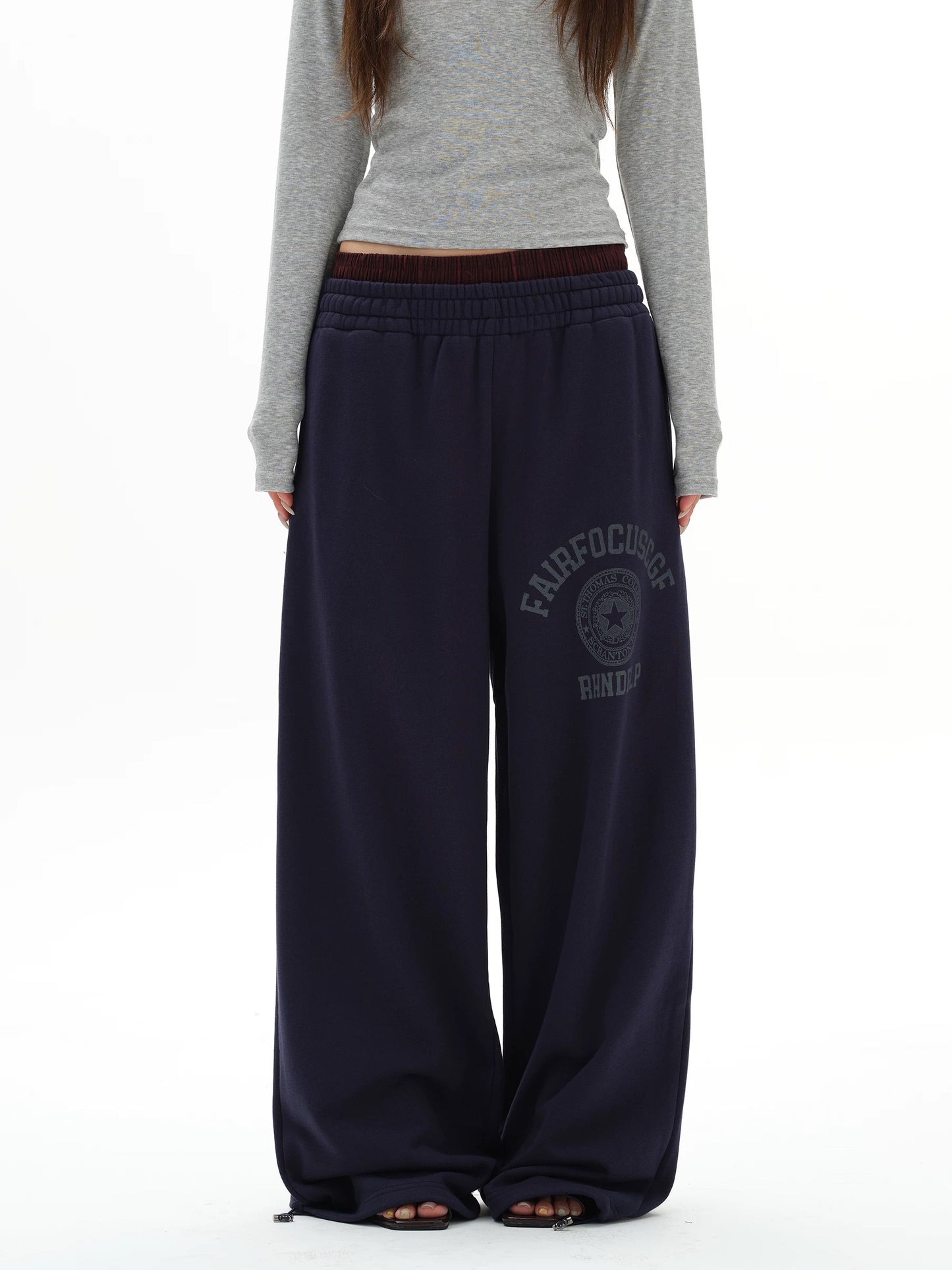 Person wearing navy sweatpants with a logo on a white background