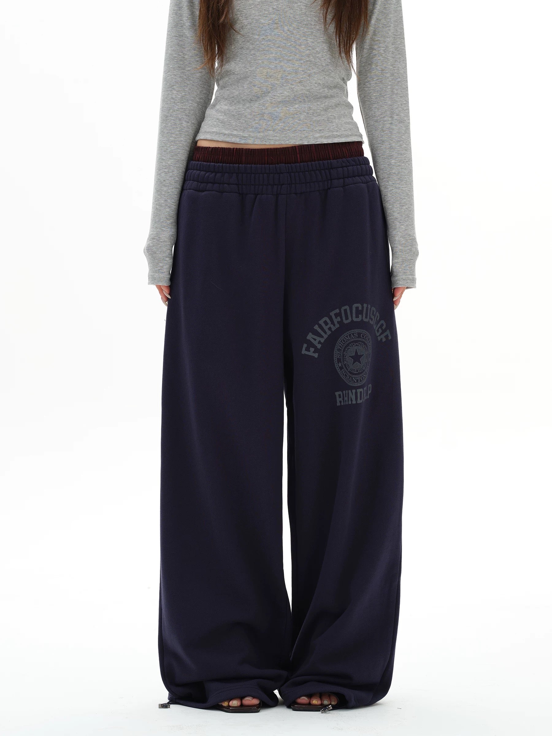 Person wearing navy sweatpants with a logo on a white background
