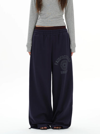Person wearing navy sweatpants with a logo on a white background