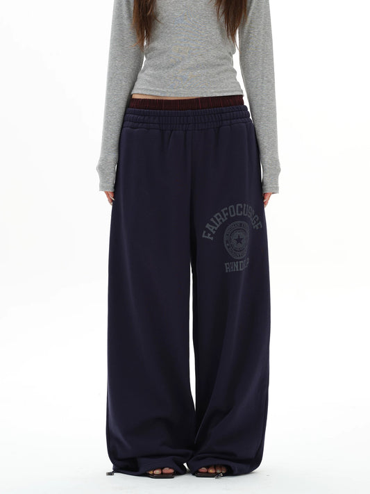 Person wearing navy sweatpants with a logo on a white background