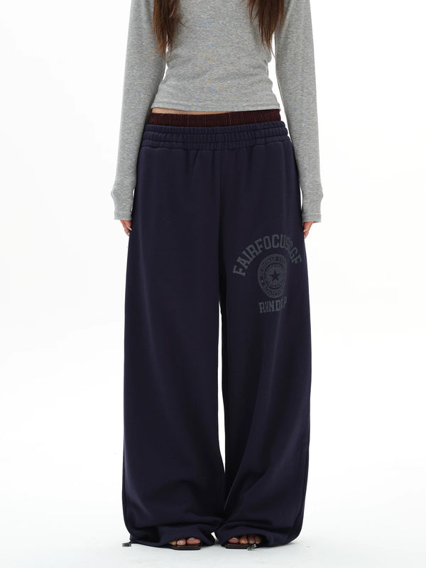 Person wearing navy sweatpants with a logo on a white background