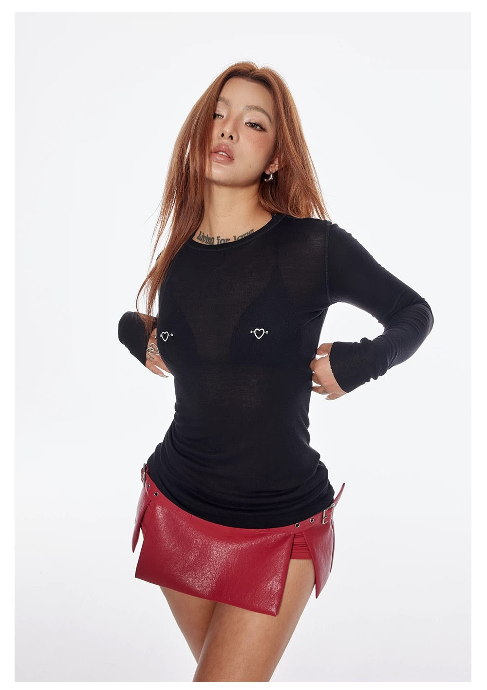 Woman wearing a black long-sleeve top and red leather skirt on a white background