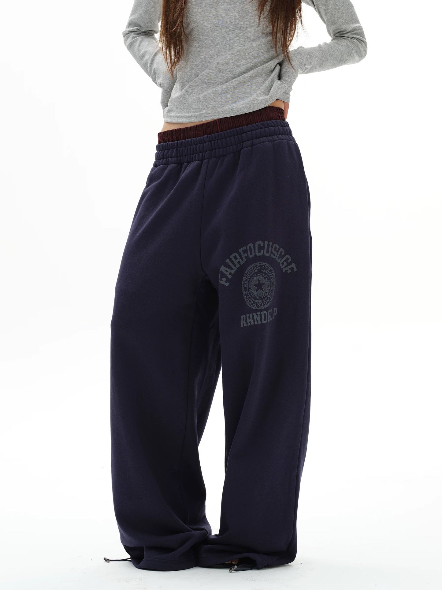 Person wearing navy sweatpants with a logo and text on a white background