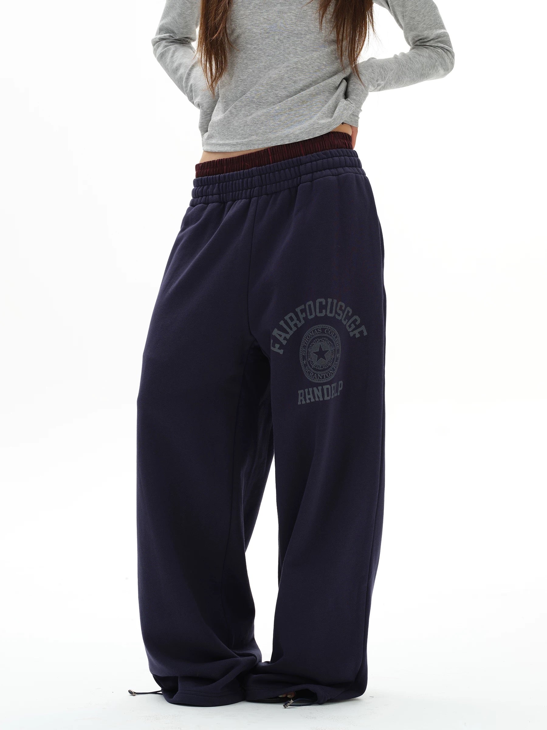 Person wearing navy sweatpants with a logo and text on a white background