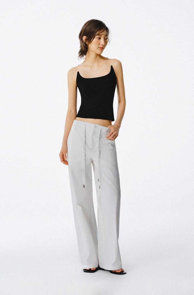 Woman wearing a black top and light gray pants on a white background