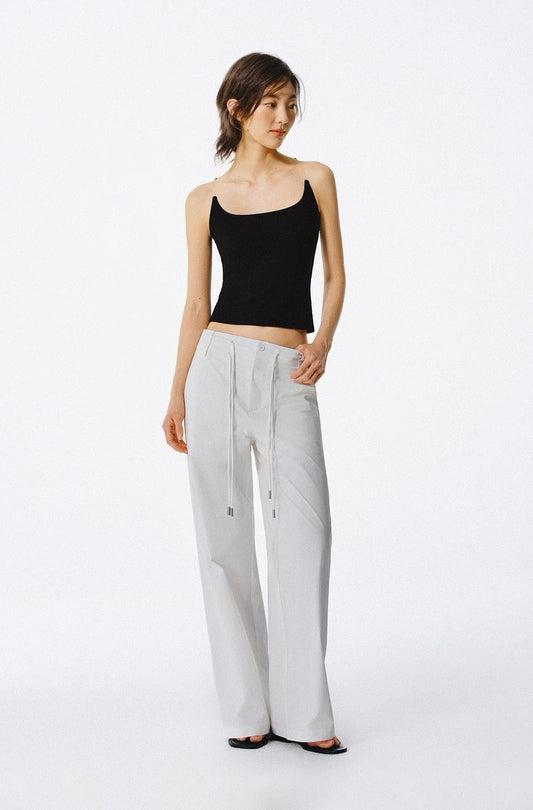Woman wearing a black top and light gray pants on a white background