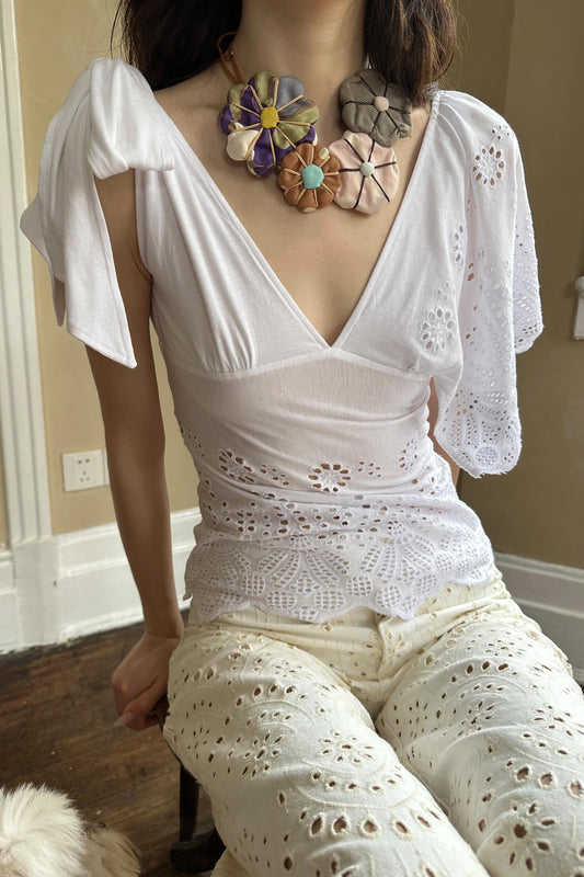 Front view of white asymmetrical lace top with one tie-up strap and one flowy sleeve.