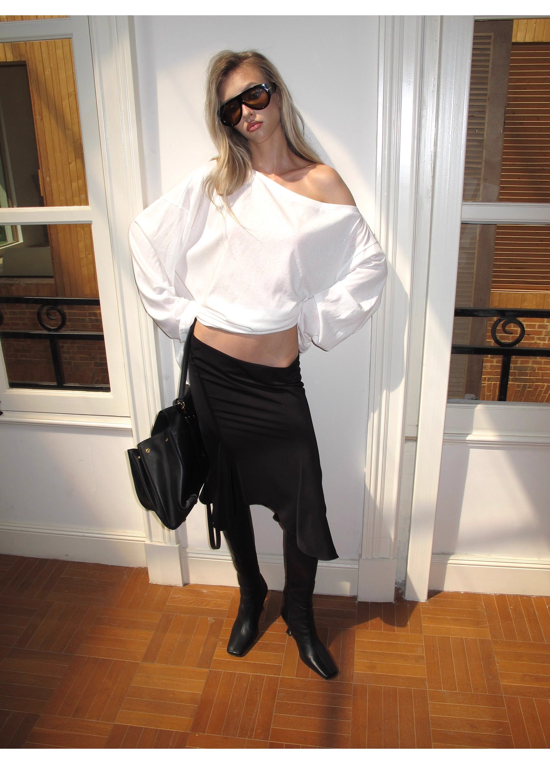 Person wearing a white top and black skirt with sunglasses indoors.