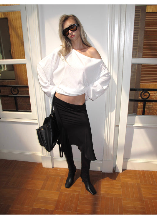 Person wearing a white top and black skirt with sunglasses indoors.