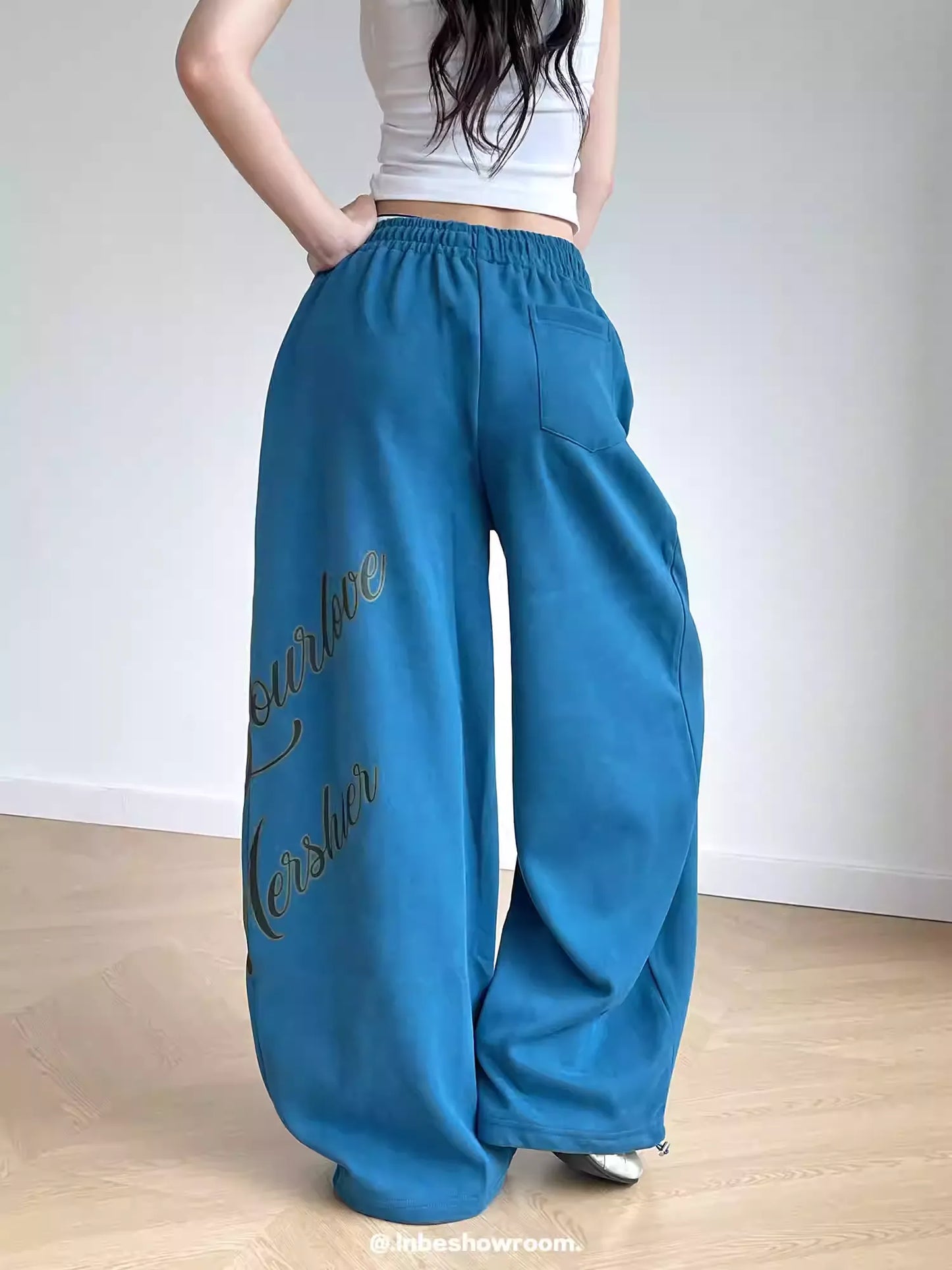 Person wearing blue wide-leg pants with text on a plain background